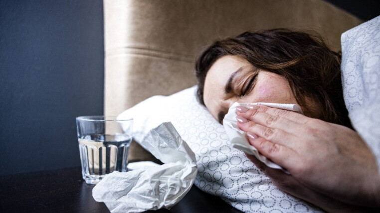 A woman wipes her nose with a tissue.