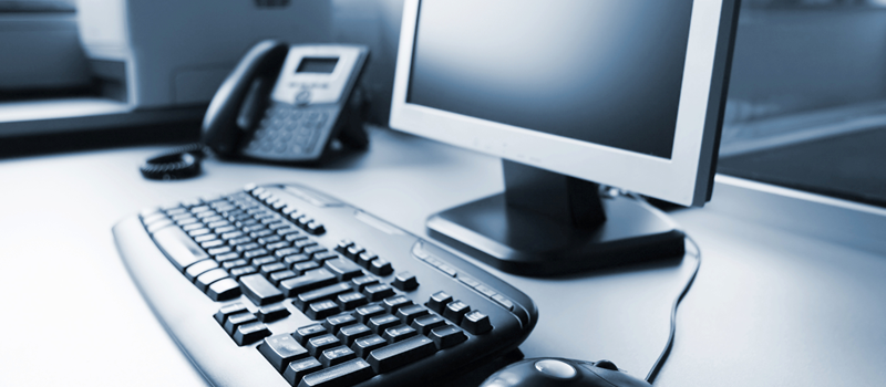 Desk with a keyboard mouse monitor and phone