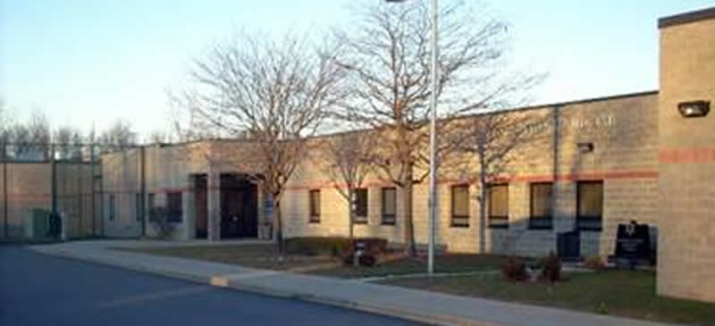 Front side of the Sheriff's office building, a tree with no leaves, and a flag pole with the American flag